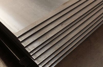Placas de acero al carbón apiladas unas sobre otras dentro de una fábrica