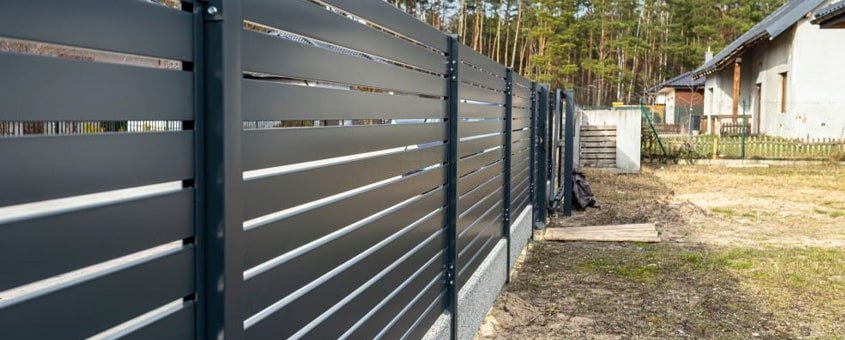 Reja de herrería con perfiles acomodados en posición horizontal protegiendo un jardín