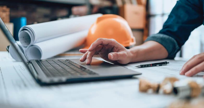 Presupuesto de obra colocado en una mesa junto a los planos del proyecto una calculadora y un casco